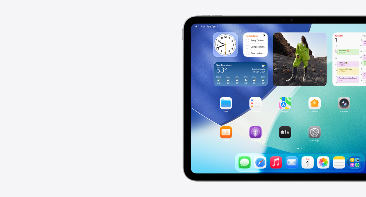 Un iPad, orientation paysage, côté gauche de l’écran uniquement, l’écran d'accueil avec des widgets superposés, notamment une horloge translucide à effet Liquid Glass, l’app Localiser et le widget Météo, deux rangées d'apps plus petites et le Dock