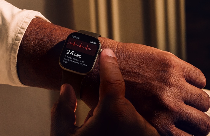 Osoba przyciskająca i przytrzymująca pokrętło Digital Crown na Apple Watch Series 11, aby sprawdzić dane dotyczące zdrowia serca w aplikacji EKG