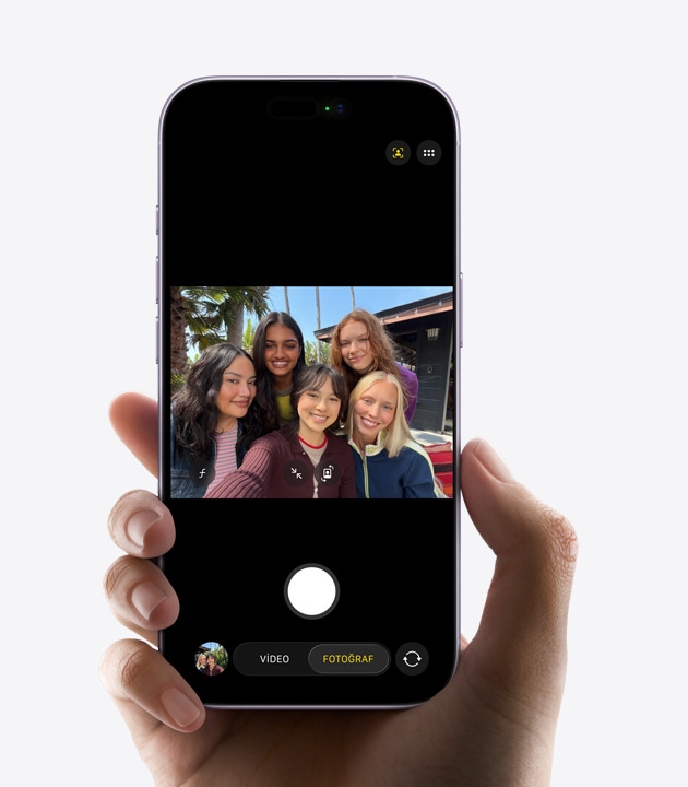 iPhone’un önden dış görünümünde Center Stage ön kamerayla üç kişinin selfie videosu çekerken yüzlerinin etrafındaki sarı karelerle otomatik kadrajlama yapıldığı gösteriliyor