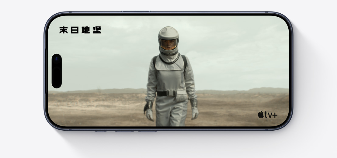 橫放的 iPhone 機身正面，展示 Apple TV+ 影集末日地堡的剪輯片段，畫面中的人身穿太空服