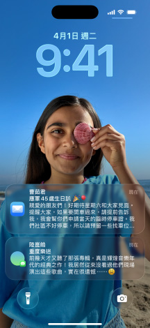 五款層疊的 iPhone 機型微微展開,每款機型彼此略微重疊。最左側的螢幕展示訊息 app 中設有背景的對話;左側第二個螢幕展示主畫面,其中包含色彩繽紛的 app 圖像;中間的機型展示鎖定畫面,其中包含照片、呈現時間的 Liquid Glass 數字設計,以及兩則顯示在螢幕底部的通知;右側第二款機型展示 Liquid Glass 設計的透明 app 圖像;最右側的機型展示 Liquid Glass 設計下的音樂播放器
